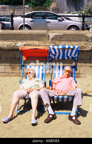 England, Hampshire, Isle of Wight, Sandown, älteres Ehepaar schlafen in Liegestühlen am Strand von Sandown Stockfoto