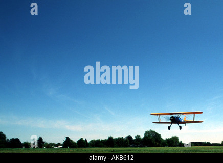 Eine bunte doppelt geflügelte Flugzeug fliegt in der Nebensaison für seine Landung auf trim grüner Wiese im Tageslicht Stockfoto