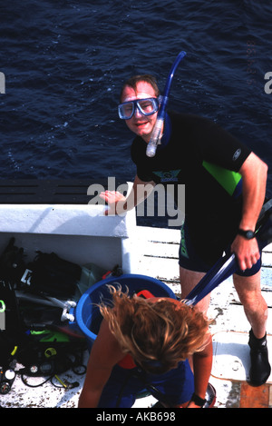 Schnorchler steht auf Boot lächelnd mit flossen in der hand Stockfoto