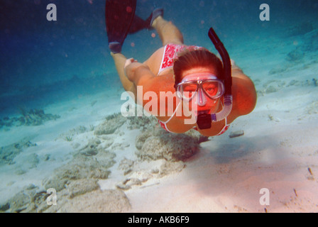 Diese weibliche Freediver, gekleidet in ein rosa Bikini Schnorchel Maske und Flossen schwimmt über den sandigen Meeresboden auf das Objektiv der Kamera Stockfoto
