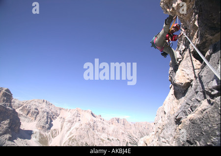 Kletterer macht eine Überbrückung Bewegung auf die Klasse 4 G Lipella Klettersteig auf Tofana de Rozes in der Nähe von Cortina italienische Dolomiten Stockfoto