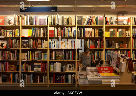 Umgeben von Büchern blättert ein Junge 12 Jahres altes Mädchen aufmerksam Kunstbücher in Grenzen Buchhandlung in Central London England Stockfoto