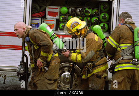 Drei Feuerwehrmänner rüsten Sie sich gegen Feuer in einem Haus Stockfoto