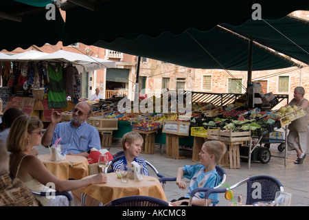 Zwei jungen teilen einen lachen beim Sitzen mit ihrer Mutter an einem Tisch in einem Straßencafé in Campo S Margherita Venedig Italien Stockfoto