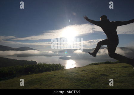 Ein stock Foto eines Mannes springen auf einem Berg bei Sonnenaufgang Stockfoto