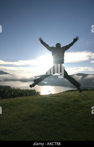 Ein stock Foto eines Mannes springen auf einem Berg bei Sonnenaufgang Stockfoto