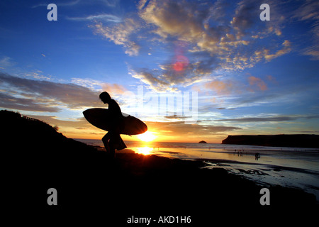 Surfer Spaziergänge bei Sonnenuntergang am Strand in Polzeath Cornwall UK Stockfoto