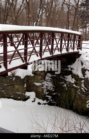 Ein Bach fließt unter einer Brücke durch einen Park in der Wintersaison und Schnee ringsum Stockfoto