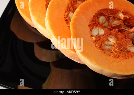 Vier Scheiben von Kürbis auf schwarze Platte mit Reflexion Makro-Größe Stockfoto