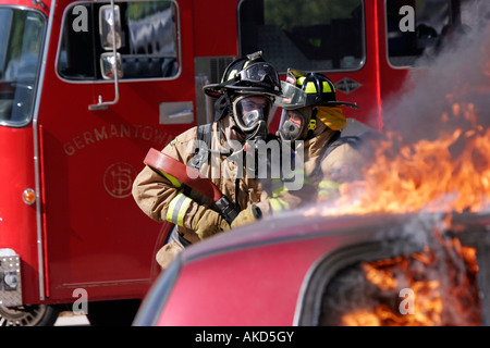 Zwei Feuerwehrleute mit einem Neuanschluß, um ein Auto zu löschen Feuer Feuerwehr Germantown Stockfoto