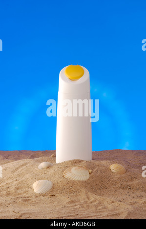 Studio-Aufnahme einer weißen Plastikflasche ohne Marke, die in den Sand mit Muscheln gelegt wurde, vor blauem Hintergrund gesehen. Stockfoto