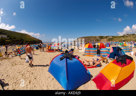 Sonnenzelte an einem geschäftigen Mawgan Porth Beach in einer britischen Hitzewelle. Cornwall, Großbritannien. Stockfoto