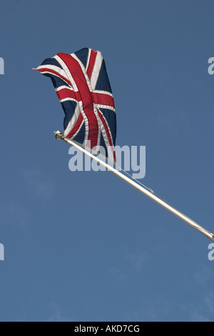 Union Jack am Fahnenmast gegen blauen Himmel zeigen Bewegung Stockfoto