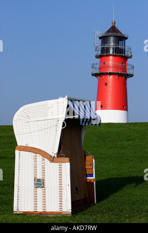 Überdachten Strandkorb gilt vor einem Leuchtturm in Büsum, Deutschland Stockfoto