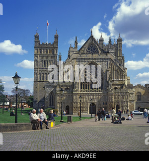 Blick auf die Westfassade und nördlichen Turm der Kathedrale von Exeter bei Sonnenschein mit Menschen sitzen und gehen Exeter Devon UK Stockfoto