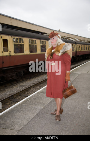 WWII Zug am Bahnhof. Reife Frau tragen Fox Pelz Stola auf der Plattform stehend Warten auf Zug in Pickering Bahnhof, Yorkshire. Stockfoto