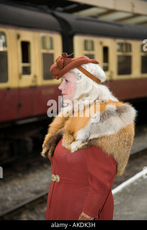 Reife Frau mit Fuchs Pelz Stola stehen auf Plattform warten auf Zug am Bahnhof Pickering, Yorkshire. Stockfoto