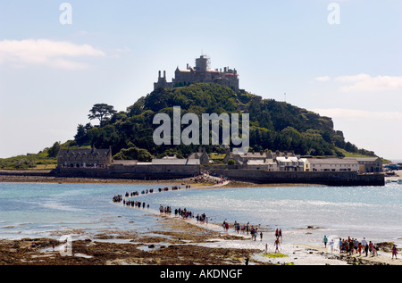 Besucher waten über den im Meerwasser untergetauchten Damm zur und von der Gezeiteninsel St. Michael's Mount in Cornwall, Großbritannien Stockfoto