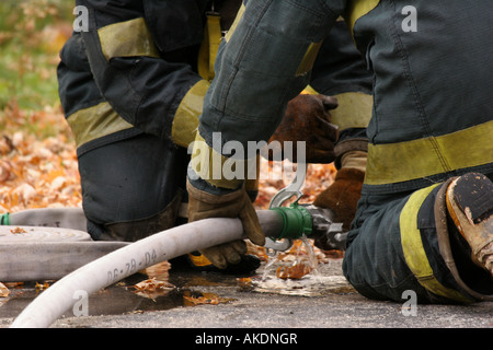 Zwei Feuerwehrleute mit Tools, um eine Schlauchverbindung anziehen, weil es undicht war Stockfoto