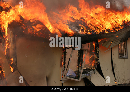 Schmutz geht fliegen, wenn die Vorderseite eines Wohnhauses in einem Feuer kollabiert Stockfoto