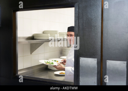 Mann-Chef hält Teller mit Essen in der Küche Stockfoto