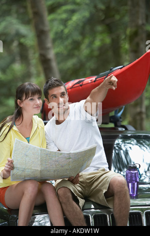 Paar sitzt auf Auto Mann zeigte ein Blick auf Karte, Stockfoto