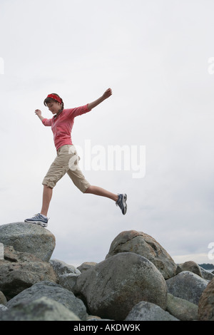 Frau mit ausgestreckten, springen auf Felsen Stockfoto