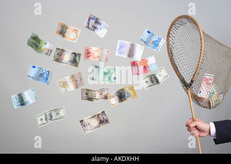 Mannes Hand Holding Schmetterlingsnetz, fangen fliegende Banknoten Stockfoto