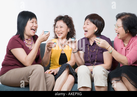 Drei Frauen in Führungspositionen und eine reife Frau hält Teetassen und lachen Stockfoto