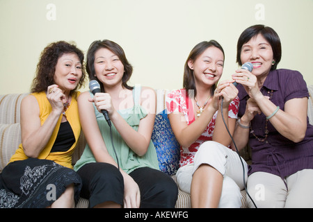 Zwei junge Frauen singen mit den Großmüttern in Mikrofone Stockfoto