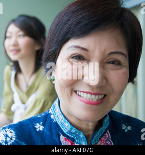 Portrait einer älteren Frau lächelnd mit ihrer Enkelin, die hinter ihr stehen Stockfoto