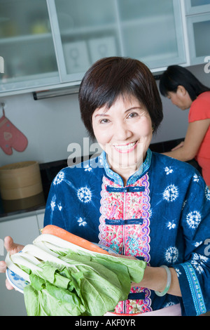 Portrait einer älteren Frau hält Gemüse und lächelnd in der heimischen Küche Stockfoto