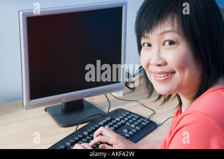 Porträt einer reifen Frau mit Hilfe eines Computers und lächelnd Stockfoto