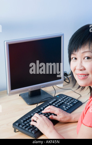 Porträt einer reifen Frau mit Hilfe eines Computers und lächelnd Stockfoto