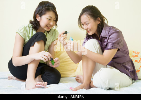 Zwei junge Frauen, die Anwendung von Nagellack auf ihre Zehennägel Stockfoto