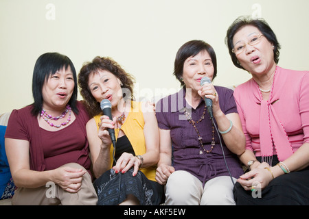 Drei Frauen in Führungspositionen und eine reife Frau singt vor Mikrofonen Stockfoto