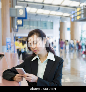 Nahaufnahme einer Geschäftsfrau mit einer Hand gehalten Gerät an einem Flughafen Stockfoto