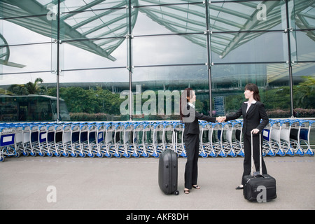 Zwei Geschäftsfrauen Händeschütteln außerhalb eines Flughafens Stockfoto