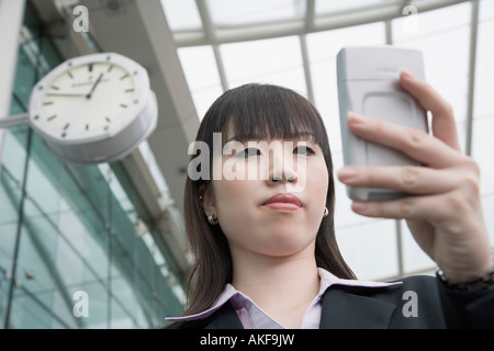 Niedrigen Winkel Blick auf eine Geschäftsfrau mit einer personenbezogenen Daten-Assistent und wartet an einer Flughafen-lounge Stockfoto