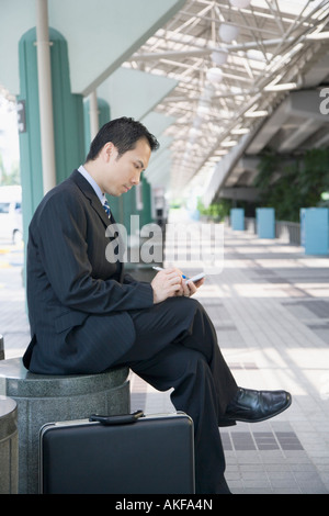 Seitenansicht eines Geschäftsmannes sitzen und mit einer Hand gehalten Gerät Stockfoto