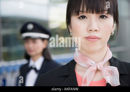 Porträt von einem weiblichen Flugbegleiter mit einer Pilotin hinter ihr Stockfoto