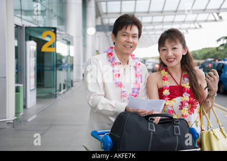 Porträt eines stehenden älteres Paar mit einem Gepäckwagen am Flughafen Stockfoto