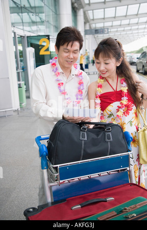 Älteres paar stehend mit einem Gepäckwagen am Flughafen Stockfoto