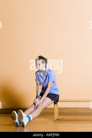 Junge Frau sitzen auf einer Bank und hält einen Badminton-Schläger Stockfoto
