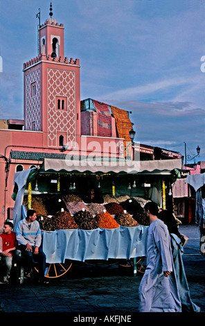 Stall verkaufen Obst und Nüssen in Djemma el Fna Marrakesch Marokko Kasbah Moschee im Hintergrund paar in lokalen Kleid vorbeigehen Stockfoto