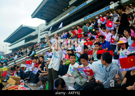 Tribünen gefüllt mit Anhängern wehende Fahnen in Sha Tin Racecourse in Hong Kong. Stockfoto