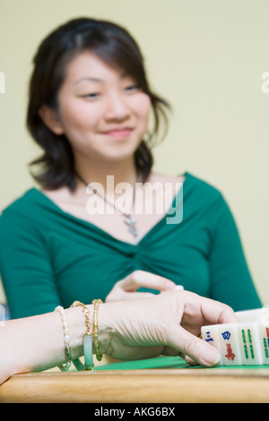 Nahaufnahme von Frauenhand mit Blöcken und eine junge Frau sitzt im Hintergrund spielen Stockfoto