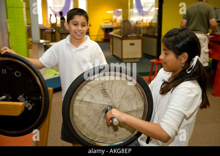 ILLINOIS Aurora Schüler experimentieren mit Ausstellungen in Sci-Tech-Händen auf Museum innen Hispanic jungen und Mädchen Zentrifugalkraft Stockfoto