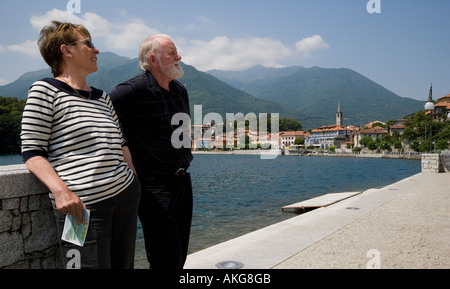 PAAR STEHEND BETRACHTEN AM MERGOZZO SEE, NORD-ITALIEN MIT DEM DORF MERGOZZO IM HINTERGRUND Stockfoto