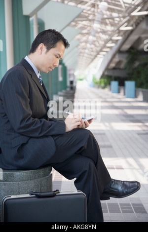 Seitenansicht eines Geschäftsmannes sitzen und mit einer Hand gehalten Gerät Stockfoto
